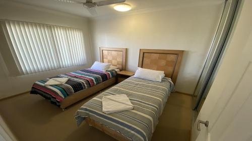 two beds in a small room with a window at Unit 36 Seafront Estate in Jurien Bay