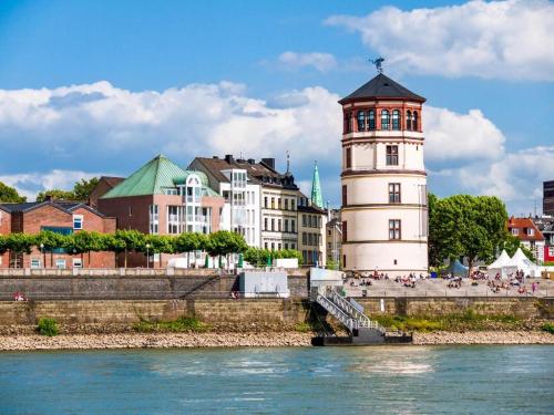 a building with a clock tower next to a river at studio m - Stylish Central City Business Apartment for 5 guests in Düsseldorf