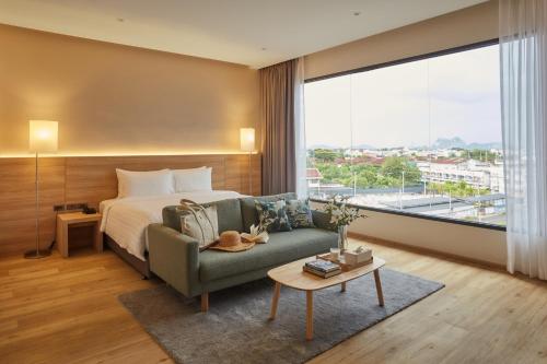 1 dormitorio con cama, sofá y ventana grande en HOTEL WISMA RATCHABURI, en Ratchaburi