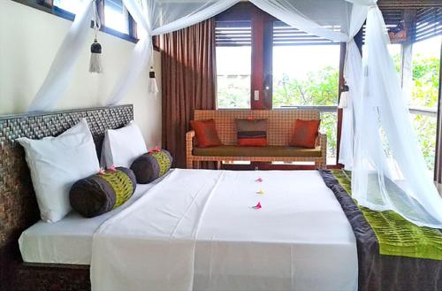 1 dormitorio con 1 cama blanca grande con almohadas en Duke's Bingin Villas, en Uluwatu