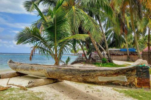 an old boat sitting on a beach with palm trees at San Blas Islands - Private Cabin Over-the-Ocean including Meals in Mandinga