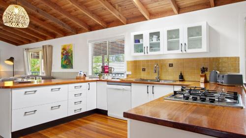a kitchen with white cabinets and a stove top oven at The Muskoka in Conjola
