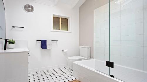 a white bathroom with a toilet and a glass shower at The Muskoka in Conjola
