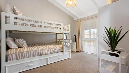 a bedroom with white bunk beds and a potted plant at The Muskoka in Conjola