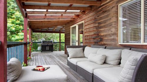 a patio with a couch and a grill on a deck at The Muskoka in Conjola