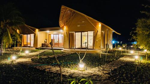 une maison avec des lumières devant elle la nuit dans l'établissement Tanoma Sumba, à Maujawa