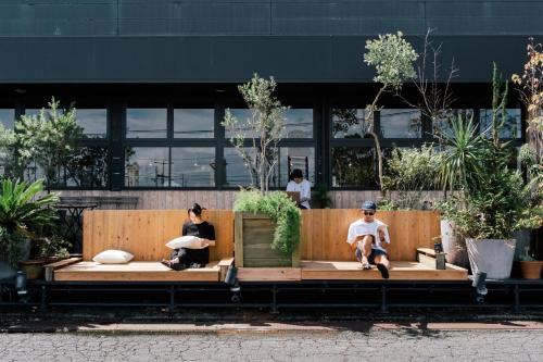 three people sitting on a bench in front of a building at FOLK FOLK Hostel, Cafe & Bar in Ise