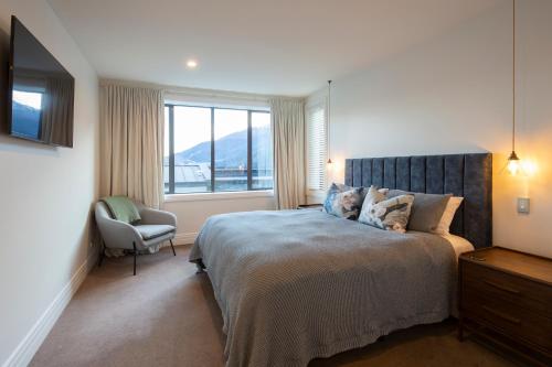 a bedroom with a bed with a chair and a window at Picture Point Villa in Queenstown