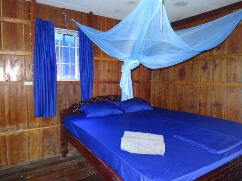 a bedroom with a blue bed with a mosquito net at Zest'house in Koh Rong Island