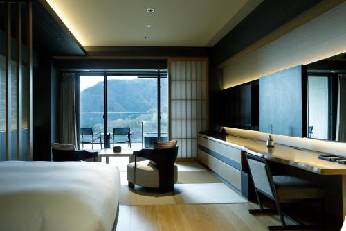 Habitación de hotel con cama, escritorio y vistas. en Hakone Gora KARAKU, en Hakone