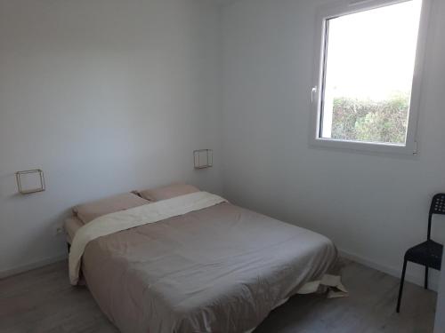 a bed in a white room with a window at La p'tite des Got in Viriat