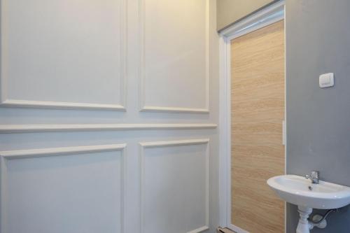 baño con puerta blanca y lavamanos en Urbanview Hotel Umbrella Dieng by RedDoorz, en Kalibeber