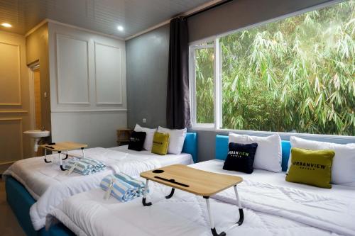 two beds in a room with a window at Urbanview Hotel Umbrella Dieng by RedDoorz in Kalibeber