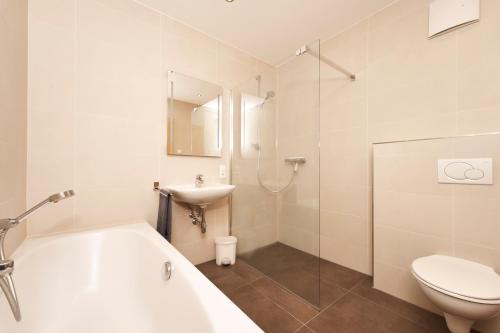 a bathroom with a tub and a sink and a toilet at Appartements Delano in Umhausen