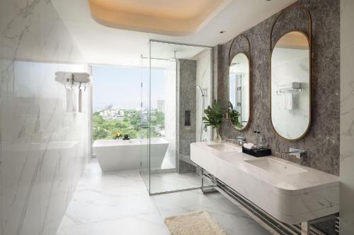 a bathroom with a sink and a tub and a mirror at Asawin Grand Convention Hotel in Bangkok