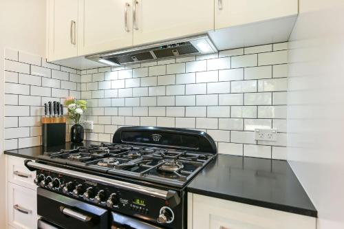 a stove in a kitchen with white tiles at Alleura House in Leura