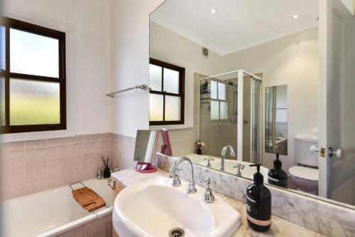 a bathroom with a sink and a tub and a mirror at Alleura House in Leura