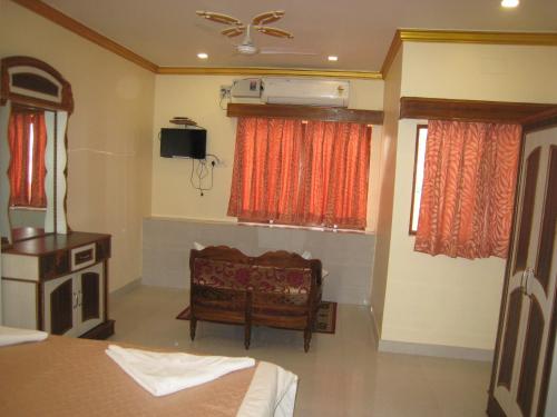 a bedroom with a bed and a chair and a tv at Kedareswar B&B in Varanasi