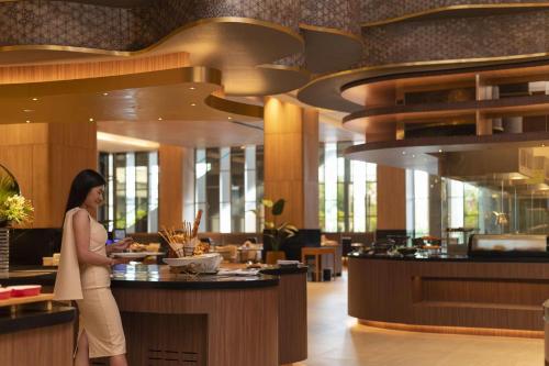 a woman standing at a counter in a restaurant at Asawin Grand Convention Hotel in Bangkok