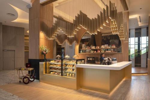 a bakery lobby with a counter with a woman in the background at Asawin Grand Convention Hotel in Bangkok