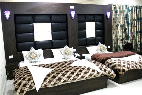 2 camas en una habitación con cabeceras de cuero negro en Hotel Samar, en Srinagar