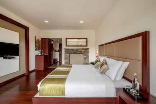 a bedroom with a large bed and a fireplace at Sterling Ooty Fern Hill in Ooty