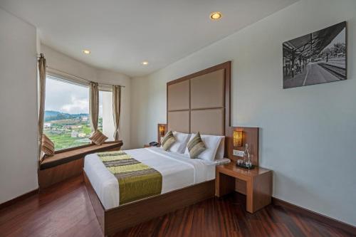 a bedroom with a large bed and a large window at Sterling Ooty Fern Hill in Ooty