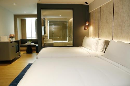 a bedroom with a large white bed and a bathroom at Miracle Grand Convention Hotel in Bangkok
