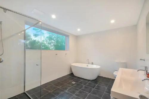 Das Bad ist mit einer Badewanne und einer Glasdusche ausgestattet. in der Unterkunft Nagual Retreat in Leura with views in Leura