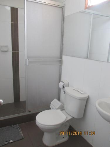 a white bathroom with a toilet and a sink at Hotel Miramar in Huarmey