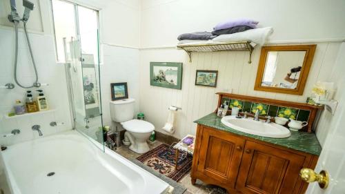 a bathroom with a tub and a sink and a toilet at Rose Pine Cottage at Leura in Leura