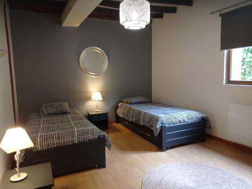 a bedroom with two beds and a mirror on the wall at Grange du Tôt in Fontenay