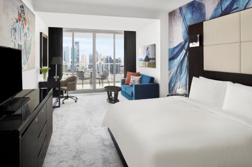 a hotel room with a bed and a television at Mövenpick Hotel Jumeirah Lakes Towers Dubai in Dubai