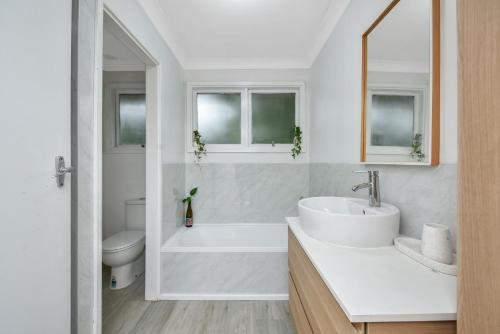 uma casa de banho branca com uma banheira e um lavatório em Tree Tops Katoomba em Katoomba