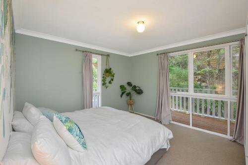 um quarto com uma cama branca e uma janela em Tree Tops Katoomba em Katoomba