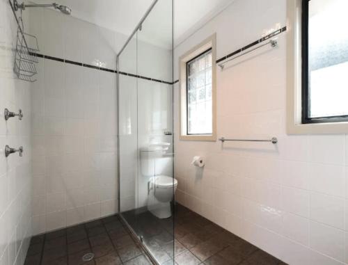 a bathroom with a toilet and a glass shower at A Vista in Forster