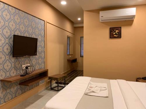 Hotel Radha krishna في أناند: غرفة نوم بسرير وتلفزيون على جدار