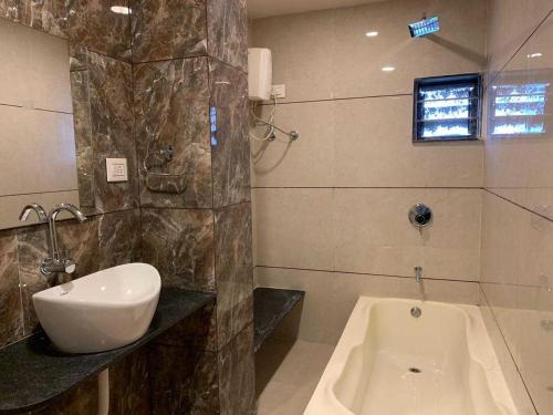 Hotel Radha krishna في أناند: حمام مع حوض وحوض استحمام