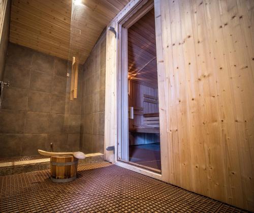 ein Bad mit einer Dusche und einer Holzwand in der Unterkunft Penzion Samoty in Železná Ruda