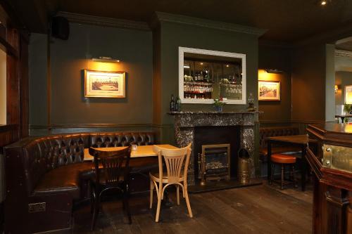 un bar con chimenea, mesa y sillas en The Avenue en Durham