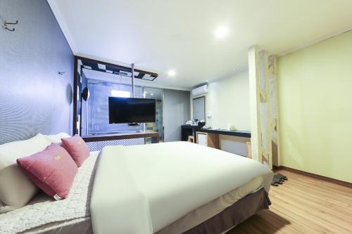 um quarto com uma cama grande e uma televisão em Central Hotel em Changwon