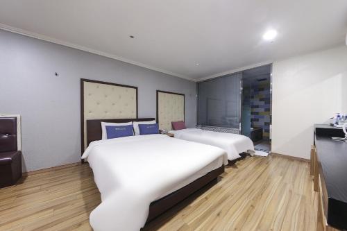 a hotel room with two beds and a desk at Central Hotel in Changwon