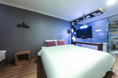 a bedroom with a large white bed and a tv at Central Hotel in Changwon