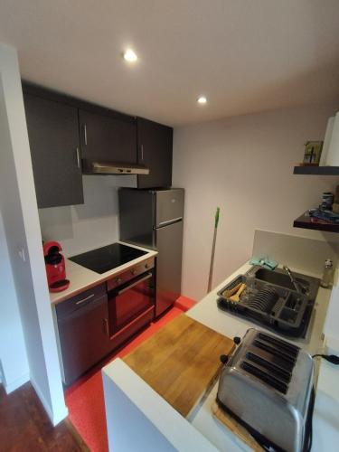 une cuisine avec des armoires noires et un comptoir dans l'établissement Studio Duplex au cœur du quartier historique!, à Bergerac