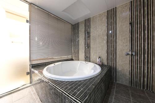 a bathroom with a large white tub in a room at Central Hotel in Changwon