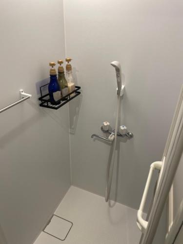 a bathroom with a shower with bottles on a shelf at Beppu hostel&cafe ourschestra in Beppu