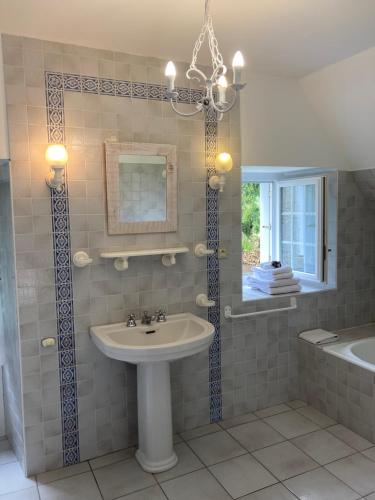 uma casa de banho com um lavatório, uma banheira e um espelho. em Manoir de Saint-Fiacre em Malansac