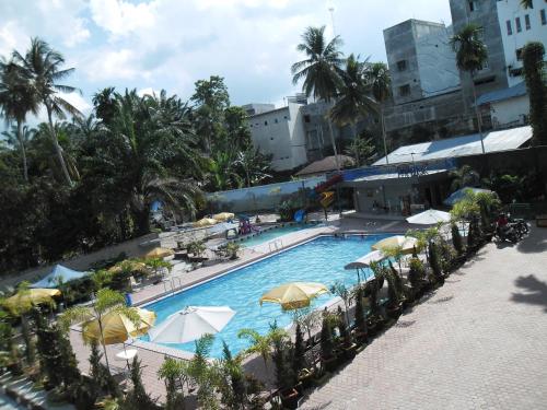 una vista aérea de una piscina con sombrillas en Permata Land Hotel & Resort, en Rantauprapat