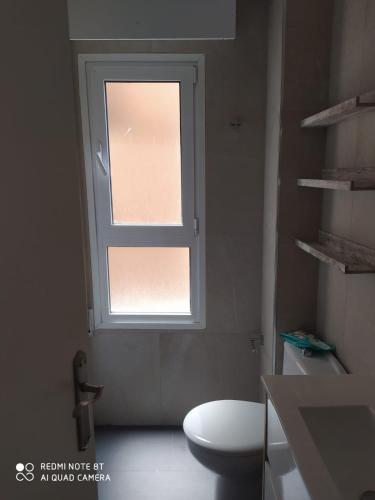 a bathroom with a toilet and a window at Aparramento Rosa in Murcia