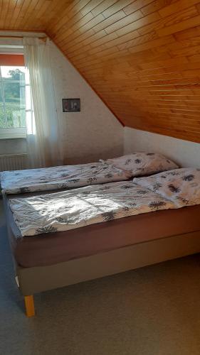 a bed in a room with a wooden ceiling at Ferienwohnung Langfeld in Kronsgaard